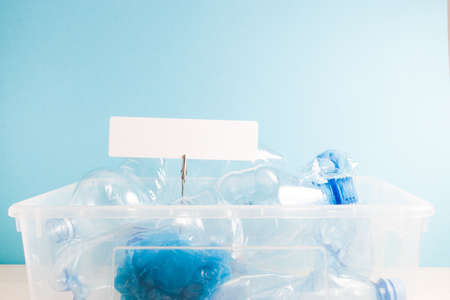 white rectangular cardboard label on a clothespin on a paper spring in a plastic waste container,...