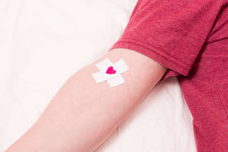 man with a band-aid on his hand, heart on a band-aid, blood donor conceptの写真素材