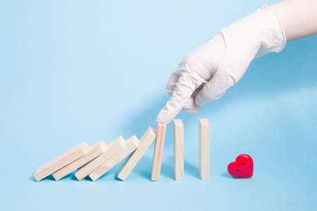 a hand in a white rubber glove leaves falling dominoes, dominoes fall on a krsanoy happy heart,...