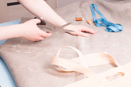 woman holds scissors to cut linen, sew fabric bag for shopping from linen, bag pattern, outline bag...