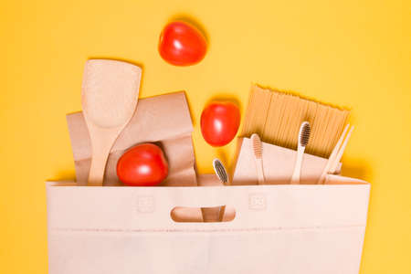 fabric eco bag with products on a yellow background, tomatoes, spaghetti in a cardboard box, paper...