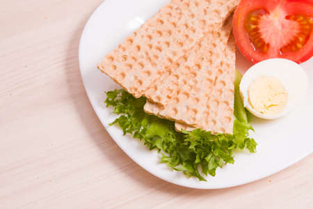 wheat bread crisps on a plate, proper and healthy nutrition concept, dietetic breakfast foods, sandwich ingredients, egg, tomato and salad on the tableの写真素材