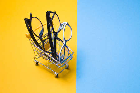 several different glasses in a small shopping trolley on a colorful background, top view, buying...