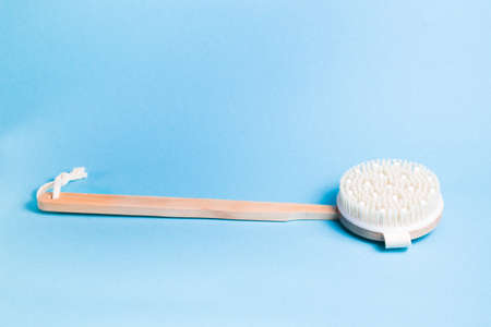 wooden brush for dry body massage on a light blue background, place copy, peeling and body care at homeの写真素材