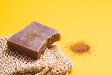 a piece of homemade chocolate soap and a knitted washcloth, a handful of ground coffee on a yellow...