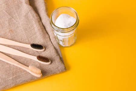natural fabric, several different bamboo brushes and a glass jar of soda on a yellow background, copy space, eco friendly lifestyle conceptの写真素材