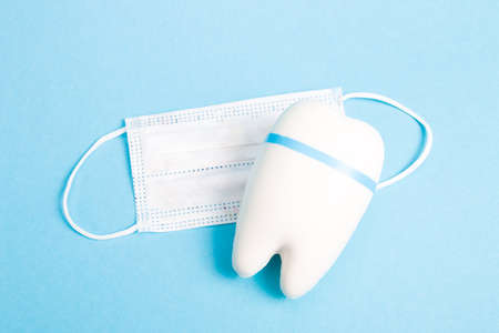 white tooth model and children's medical visceral mask on a blue background copy space, dentistry...