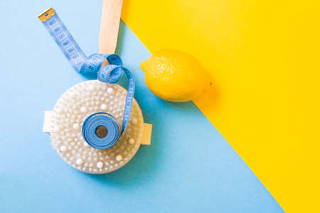 blue measuring tape on a wooden brush with natural pile of cactus and lemon on a yellow and light blue background copy space top view, anti-cellulite massage conceptの写真素材