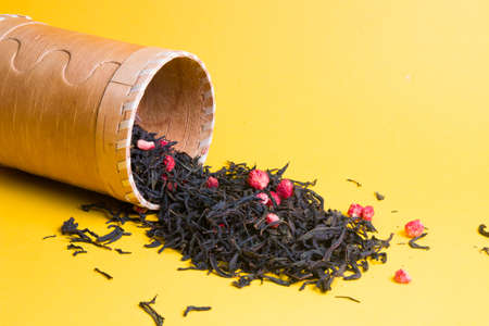 tea with dried strawberries in a box of birch bark, strawberry tea in a wooden box on a yellow background, copy space, sprinkled berries and dry tea leavesの写真素材