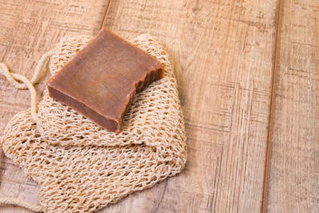 cocoa soap made from natural ingredients on a knitted washcloth, homemade soap on a wooden background, zero life-style waste, cocoa bar on a cotton thread washclothの写真素材
