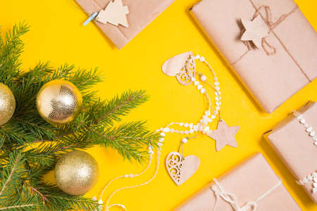 fir branches, shiny gold balls for the Christmas tree and several gift boxes packed in kraft paper...