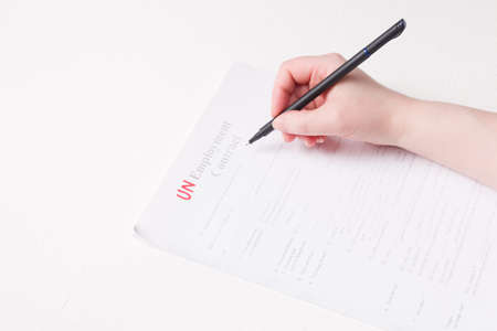 woman signs a black letter of dismissal, fired during the crisis, unemployment concept, white background, copy spaceの写真素材