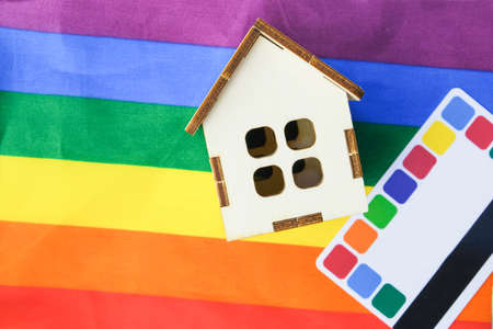 credit card and a small wooden house on the flag of the lgbt community, purchase of suburban real estate by same-sex couplesの写真素材