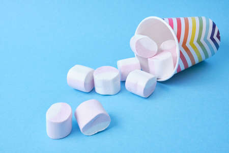 marshmallows with fruit juice in a festive paper cup with geometric bright pattern on blue...