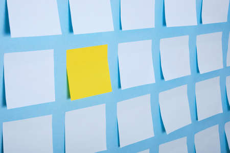 a lot of light blue and one yellow paper stickers on a blue background, a pattern of stickers for notesの写真素材