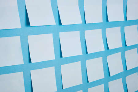 a lot of light blue paper stickers on a blue background, a pattern of stickers for notes, mock up, selective focusの写真素材