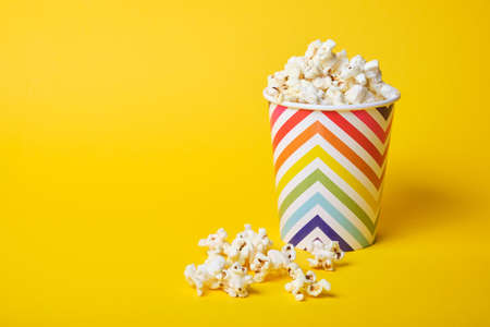 popcorn in bright holiday paper cup on yellow backgroundの写真素材