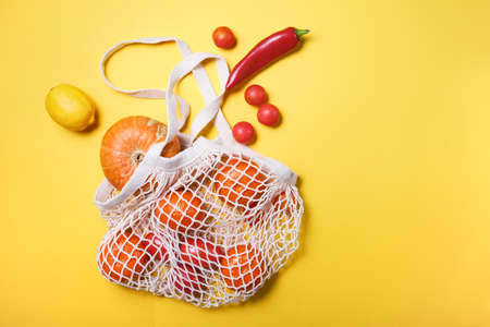 Juicy and fresh vegetables and fruits in ecological cotton reusable string bag, alternative to plastic bags, on white background. top view copy spaceの写真素材