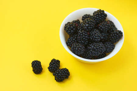 Dewberry. Blackberries in a wooden bowl on a light table. Fresh blackberries in a bowl close-up. Space for textの写真素材