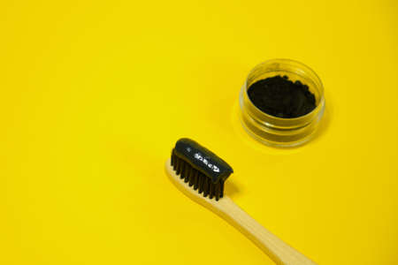 Toothbrush with black charcoal toothpaste. Black toothpaste on toothbrush with activated charcoal pills.の写真素材
