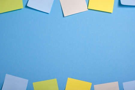 bright colored sticky notes on a blue background in two rowsの写真素材