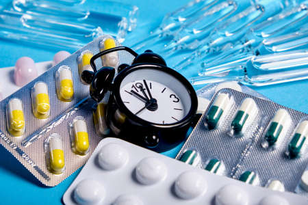 Packaging of tablets and pills on the table with clock in the middle. Medicineの写真素材
