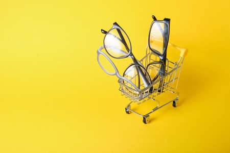 eyeglasses in shopping cart on yellow backgroundの写真素材