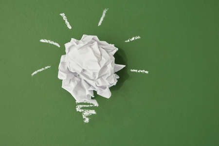 crumpled paper in the shape of a light bulb on a green chalk board background, planet pollution conceptの写真素材