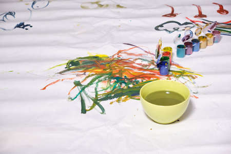 a small child draws with paints on a large sheet of paper, a child draws flowers, sun and skyの写真素材