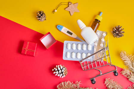 shopping cart with medicines on yellow-red background, buying medicines before christmas and new year, cold and flu seasonの写真素材
