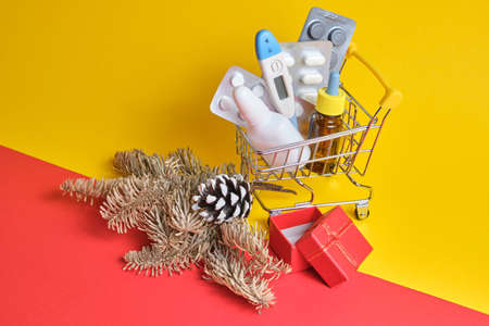 shopping cart with medicines on yellow-red background, buying medicines before christmas and new year, cold and flu seasonの写真素材