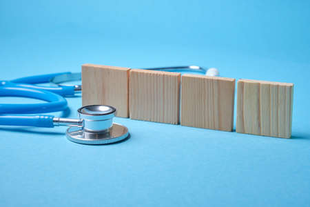 medical stethoscope and four wooden squares on a blue background
