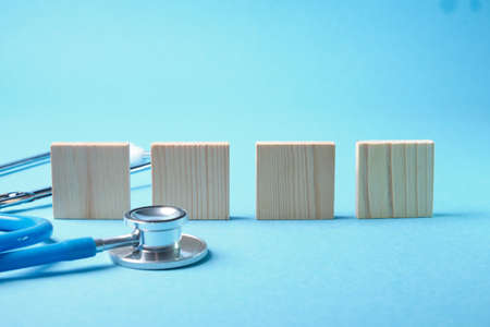 medical stethoscope and four wooden squares on a blue backgroundの写真素材