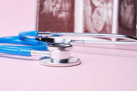 a medical stethoscope and embryo picture on pink background