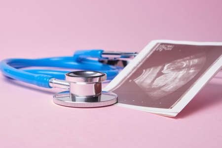a medical stethoscope and embryo picture on pink background