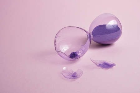 broken glass hourglass with purple sand on a pink background, time conceptの写真素材