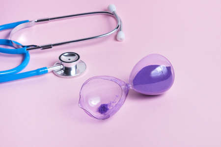 Time check up and Time management. stethoscope and broken hourglass on pink backgroundの写真素材