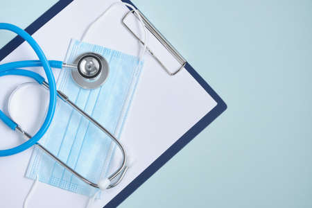 Medical mask, syringe, stethoscope and note pad on blue backgroundの写真素材