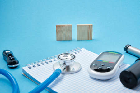 clean block with spring, stethoscope, glucose meter, lancet and syringe pen with insulin on a blue background, daibet day concept, diabetes diagnosisの写真素材