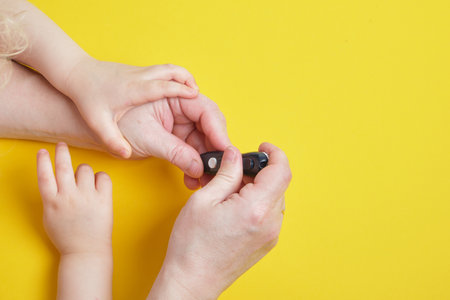 grandmother is doing glucose level finger blood test to child, cope space top viewの写真素材
