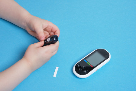 small child presses the button glucose meter, blood glucose meter, childhood diabetes, child health care blue backgroundの写真素材