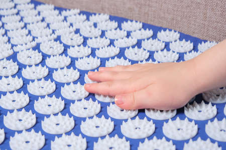baby palm on a blue massage acupuncture mat with white massage tips, massage mat for relaxation and treatmentの写真素材