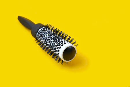 Professional black hair brush on yellow background copy spaceの写真素材