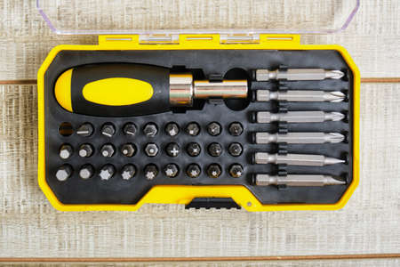 screwdriver and nozzles in a plastic box, copy place, screwdriver nozzles on wooden background
