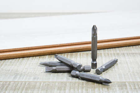 Set of metal bits for screwdriver on laminate flooring copy space