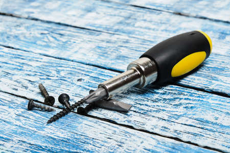 Screwdriver, screws and wooden bars on wooden background copy space