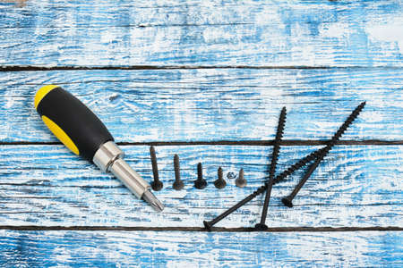 Screwdriver, screws and wooden bars on wooden background copy space