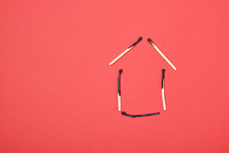 silhouette of a house made of burnt matches on a red background copy spaceの写真素材