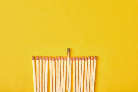 new matches and one burnt one are laid out in a row on a yellow background top viewの写真素材