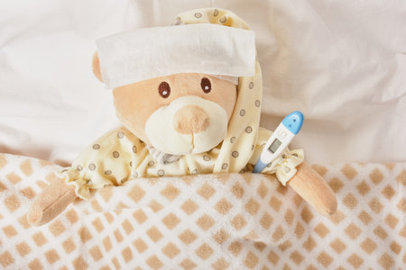 Teddy bear lying sick in bed with with thermometer. Healthcare and medical concept. caring for...